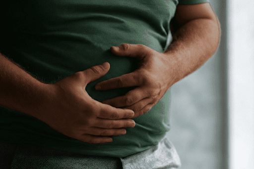 Man holding his stomach while paying attention to his body's natural hunger signals
